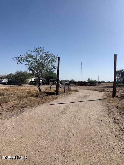 view of street featuring a rural view, driveway, and a gated entry