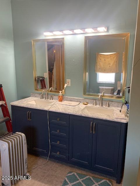 full bath featuring radiator heating unit, tile patterned flooring, double vanity, and a sink
