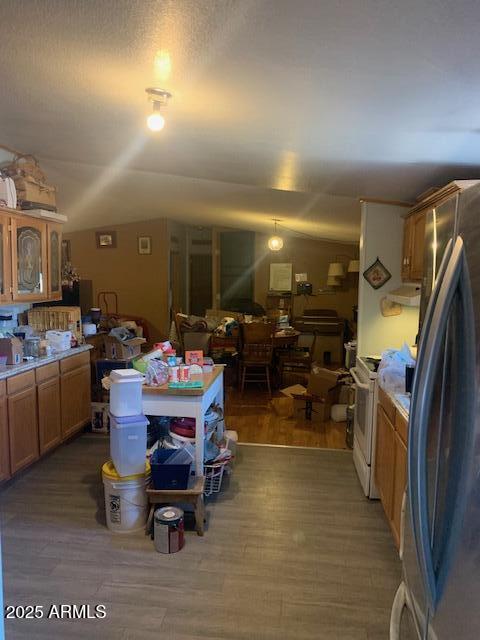 interior space with light countertops, vaulted ceiling, freestanding refrigerator, and wood finished floors