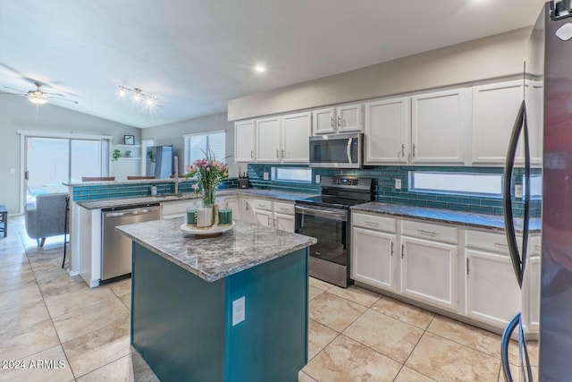 kitchen featuring kitchen peninsula, appliances with stainless steel finishes, white cabinetry, and lofted ceiling