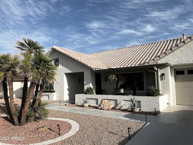 view of front facade with an attached garage, driveway, a tile roof, and stucco siding