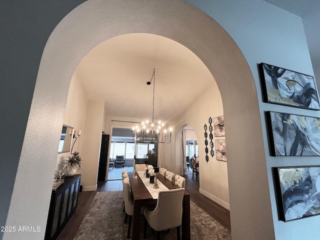 dining space with baseboards, arched walkways, a chandelier, and dark wood-style floors