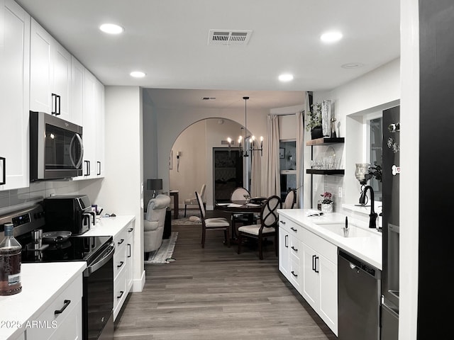 kitchen with backsplash, visible vents, a sink, stainless steel appliances, and white cabinetry