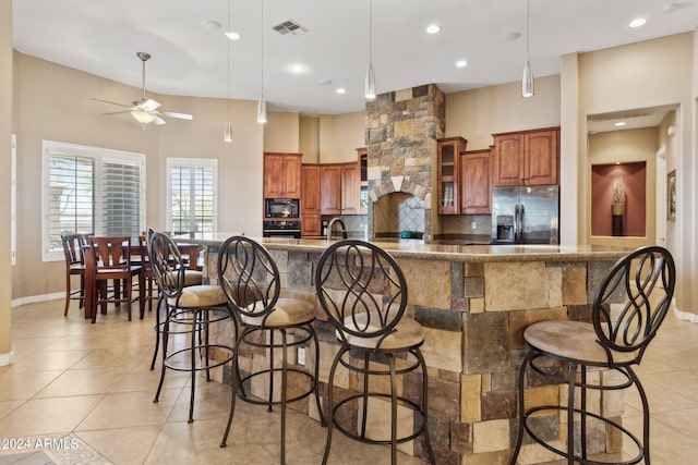 kitchen with tasteful backsplash, a breakfast bar area, light tile patterned floors, black appliances, and ceiling fan