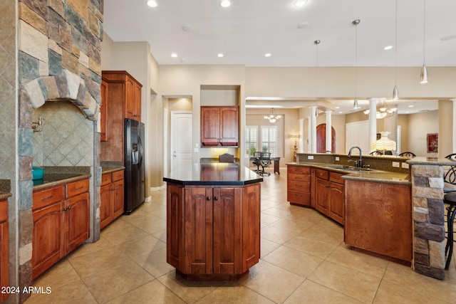 kitchen with a chandelier, a kitchen island with sink, sink, refrigerator with ice dispenser, and decorative light fixtures