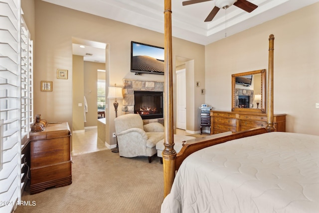 carpeted bedroom with a stone fireplace and ceiling fan