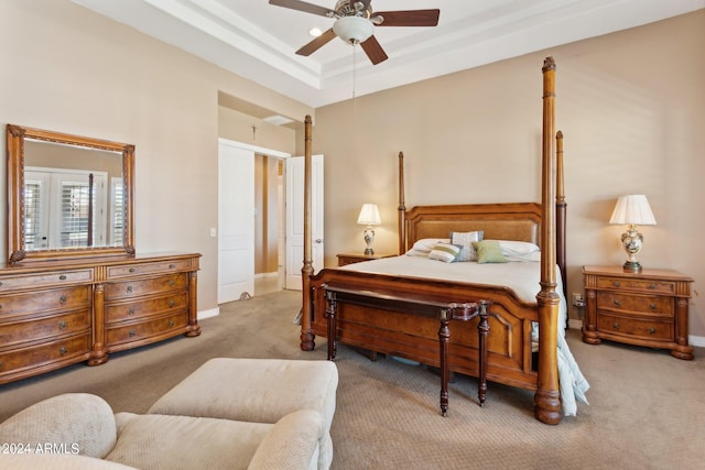 bedroom featuring a raised ceiling, ceiling fan, and light colored carpet