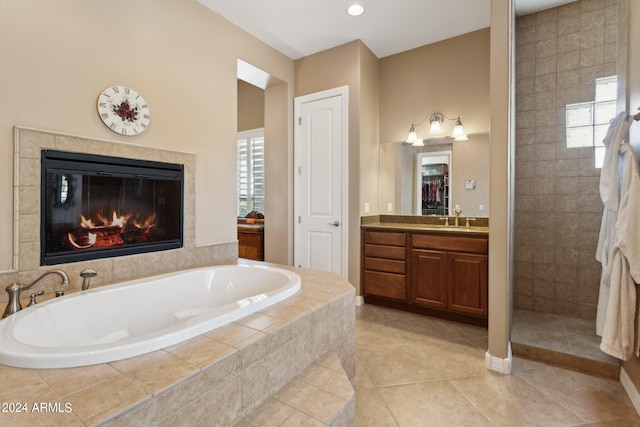 bathroom with vanity, a tiled fireplace, separate shower and tub, and tile patterned flooring