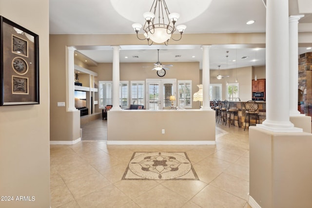 interior space featuring ceiling fan with notable chandelier and decorative columns