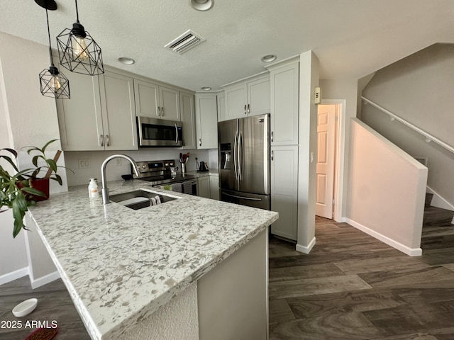 1060 E Louis Way, Tempe, AZ 85284 - kitchen featuring appliances with stainless steel finishes, a peninsula, dark wood finished floors, decorative light fixtures, and light stone countertops