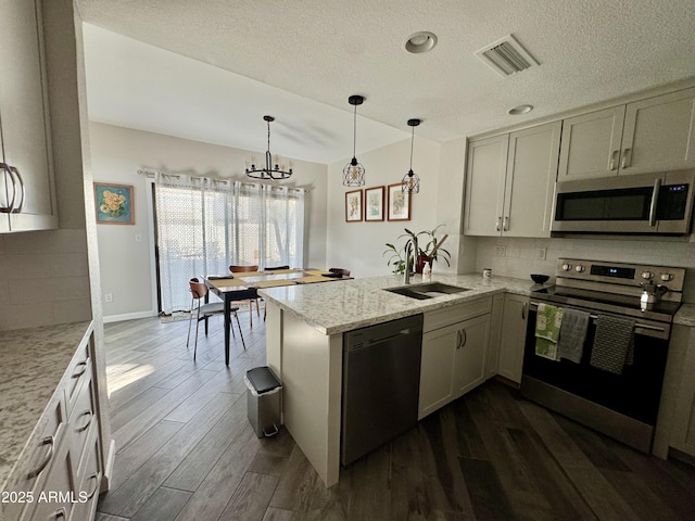 1060 E Louis Way, Tempe, AZ 85284 - kitchen featuring stainless steel appliances, a peninsula, decorative backsplash, dark wood finished floors, and a textured ceiling