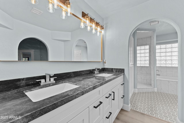 bathroom with a garden tub, double vanity, a sink, and visible vents