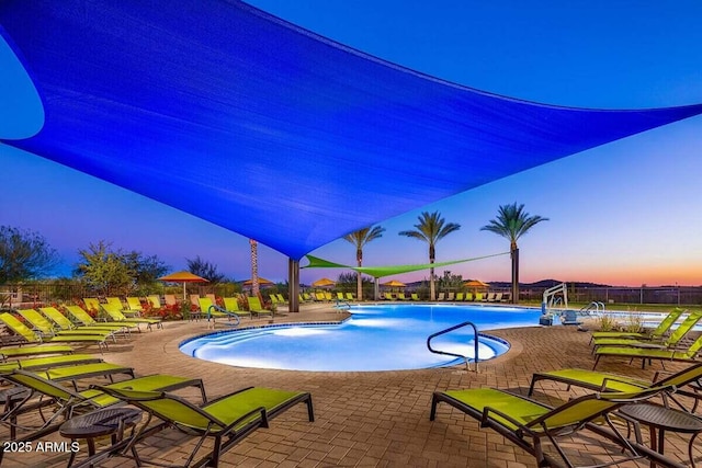 pool at dusk with a patio area