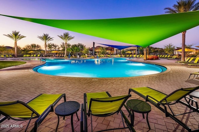 pool at dusk featuring a patio