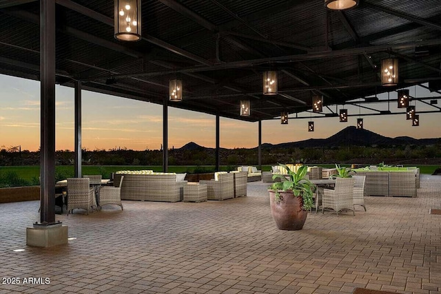 patio terrace at dusk featuring a mountain view and an outdoor hangout area