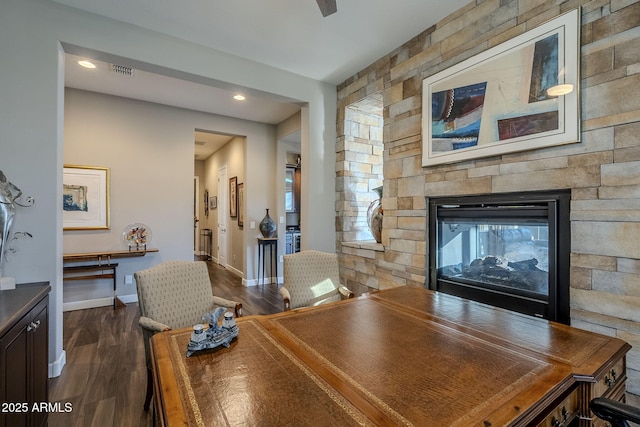 dining room featuring dark hardwood / wood-style floors and a stone fireplace