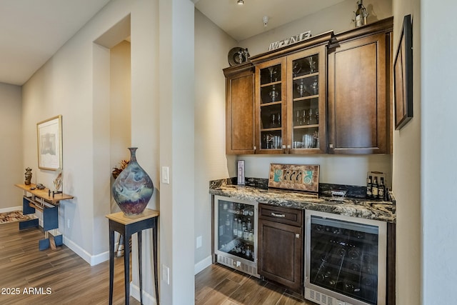 bar featuring dark stone countertops, dark brown cabinetry, dark wood-type flooring, and beverage cooler