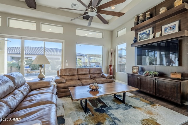 living room with dark hardwood / wood-style floors, a healthy amount of sunlight, and a towering ceiling