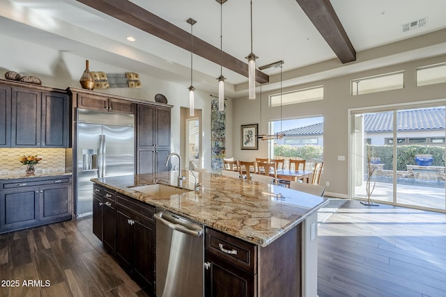 kitchen featuring sink, an island with sink, hanging light fixtures, and appliances with stainless steel finishes