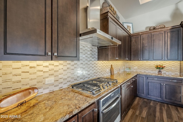 kitchen with decorative backsplash, light stone counters, wall chimney range hood, and appliances with stainless steel finishes