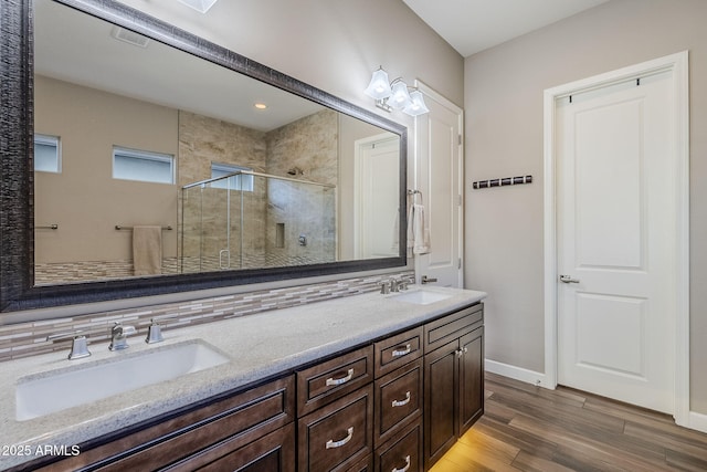 bathroom featuring tasteful backsplash, vanity, a shower with shower door, and wood-type flooring