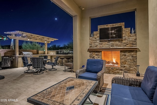 view of patio featuring an outdoor stone fireplace, area for grilling, and an outdoor kitchen