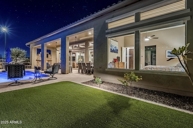 back house at night featuring a fireplace and a patio