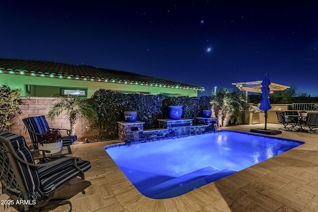 pool at twilight with pool water feature and a patio area