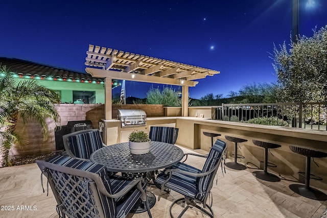 patio at night with an outdoor kitchen, an outdoor bar, and grilling area