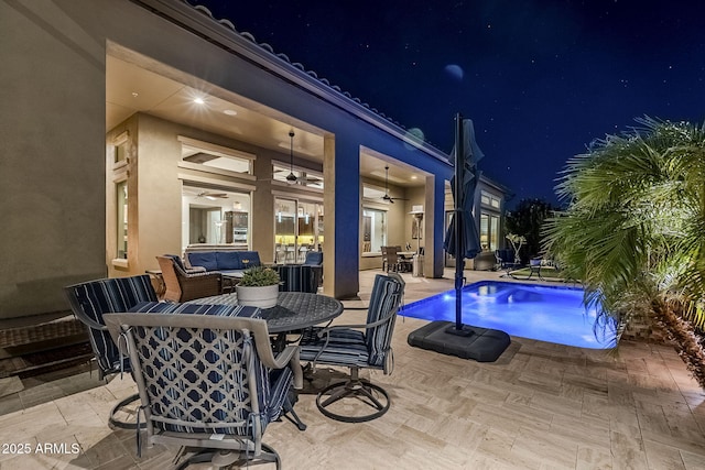 pool at twilight featuring ceiling fan, an outdoor living space, and a patio