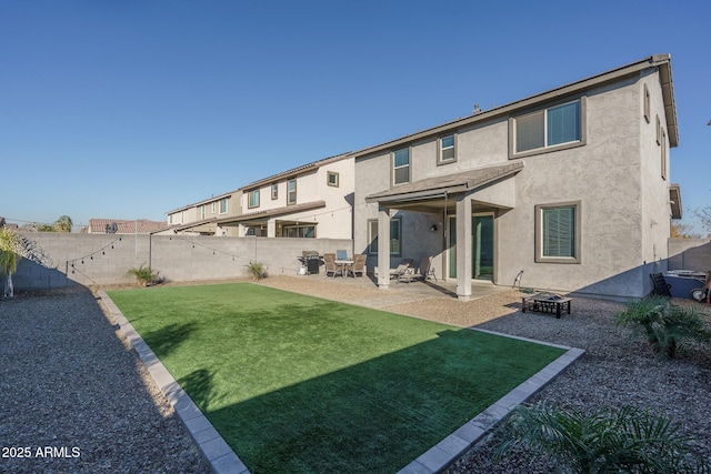 back of house with a lawn, a patio area, and a fire pit