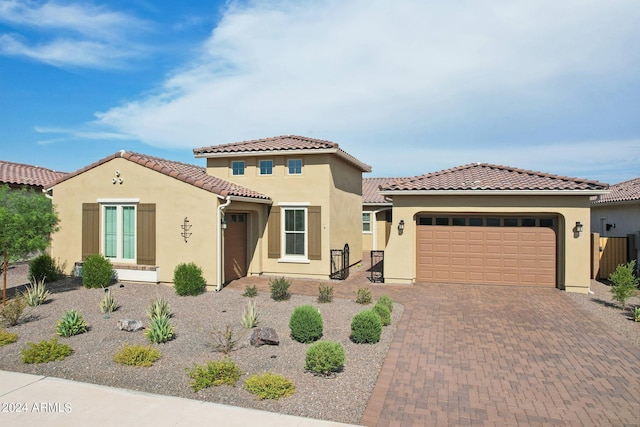 mediterranean / spanish home featuring a garage, decorative driveway, a tile roof, and stucco siding