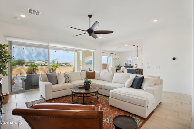 living room with sink and ceiling fan with notable chandelier