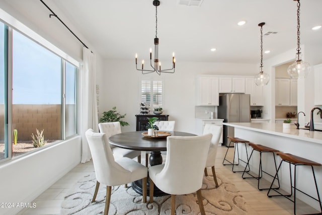 dining room featuring sink, light hardwood / wood-style floors, and a chandelier