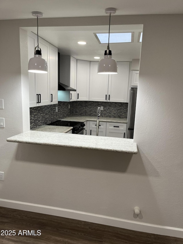 kitchen with freestanding refrigerator, backsplash, electric range, and wall chimney exhaust hood