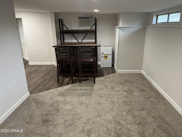 basement featuring carpet, baseboards, wood finished floors, and a wall mounted AC