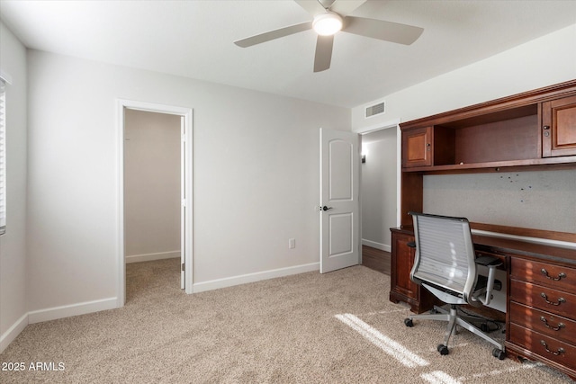 unfurnished office featuring light carpet, baseboards, visible vents, and a ceiling fan