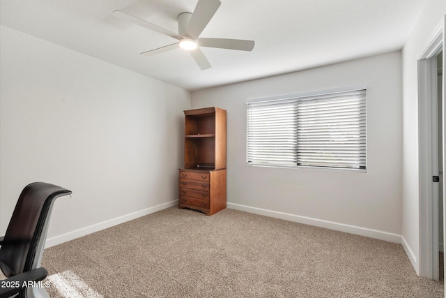 unfurnished office with light colored carpet, ceiling fan, and baseboards