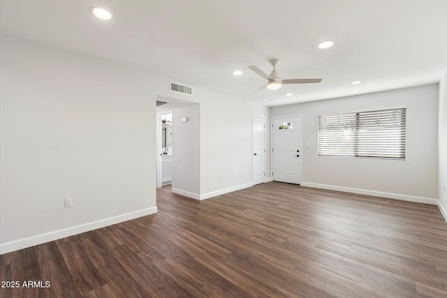 empty room with dark wood-style floors, recessed lighting, visible vents, and baseboards