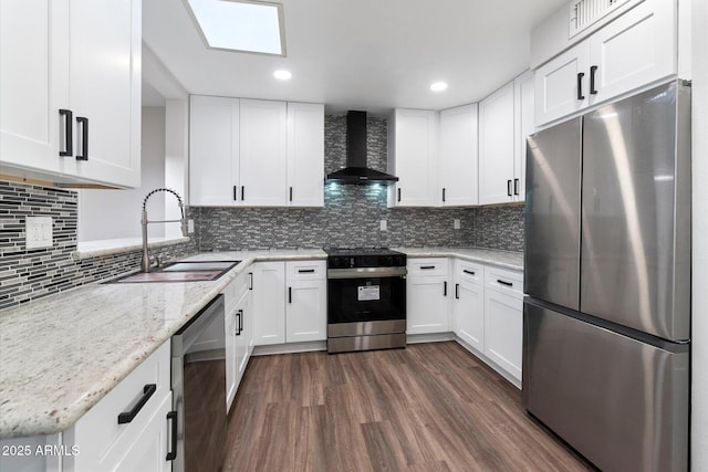 kitchen featuring white cabinets, wall chimney range hood, stainless steel appliances, and a sink