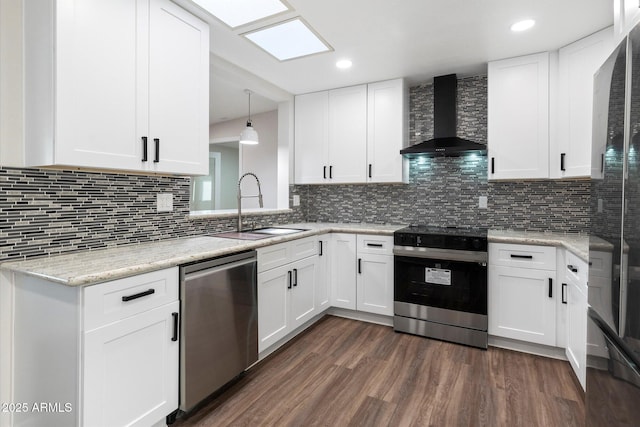 kitchen featuring stainless steel appliances, dark wood-type flooring, a sink, wall chimney range hood, and decorative backsplash