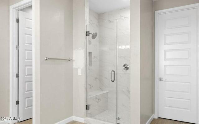 bathroom featuring a marble finish shower and baseboards