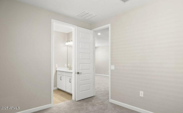 unfurnished bedroom featuring baseboards, connected bathroom, visible vents, and light colored carpet