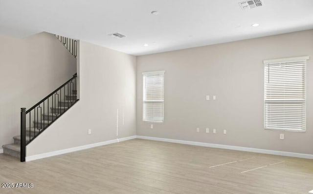 empty room featuring stairway, baseboards, visible vents, and light wood finished floors