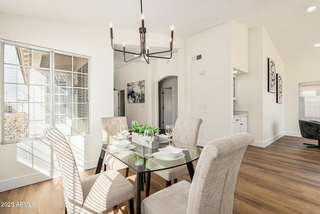 dining area with a chandelier, hardwood / wood-style floors, and vaulted ceiling