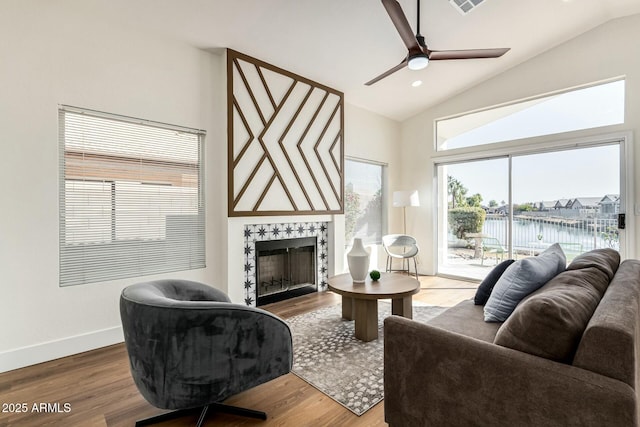 living room with ceiling fan, a water view, wood-type flooring, and vaulted ceiling