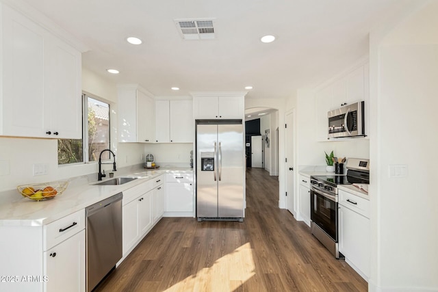 kitchen with white cabinets, sink, light stone countertops, appliances with stainless steel finishes, and dark hardwood / wood-style flooring