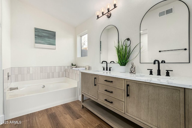 bathroom featuring a bathing tub, vanity, wood-type flooring, and lofted ceiling