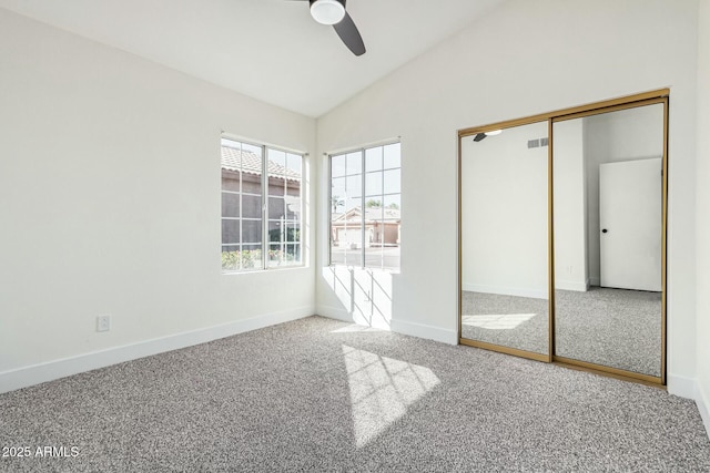 unfurnished bedroom featuring carpet flooring, vaulted ceiling, a closet, and ceiling fan