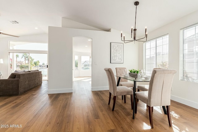 dining room with a notable chandelier, wood-type flooring, and lofted ceiling